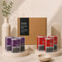 A detox supplement set displayed in a styled studio setup. The set includes a large brown cardboard box labeled 'Daily Heavy Metal Detox' in the background, with multiple individual product boxes in purple and red in the foreground on round pedestals.
